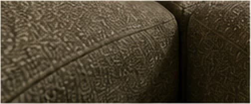 Close view of a curved cushion seam in olive fabric.